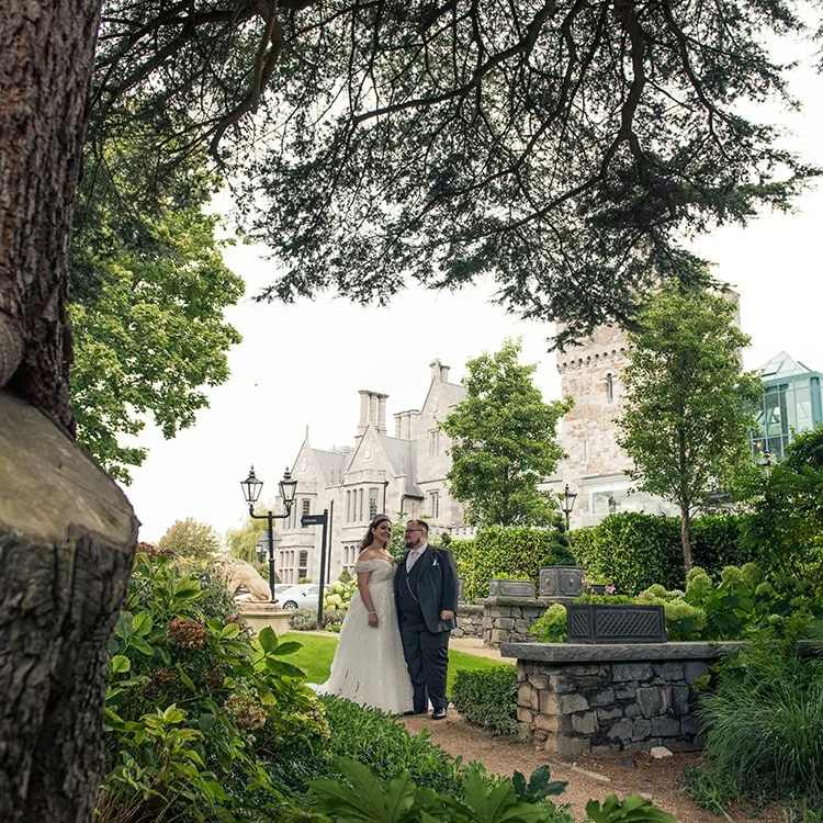 Two people stand engaged in gaze at the front of Clontarf Castle Wedding Venue in Dublin